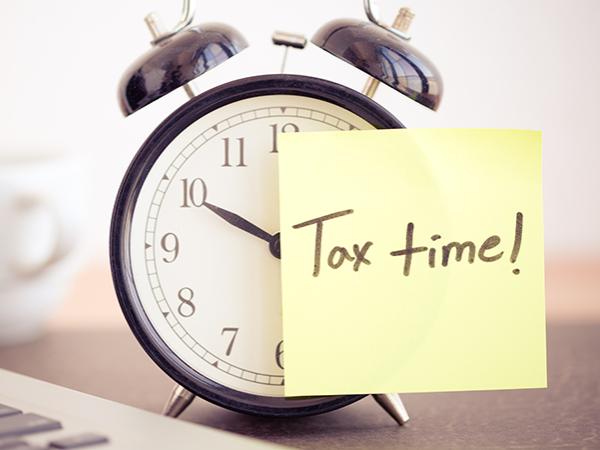 an alarm clock with a note reading tax time!