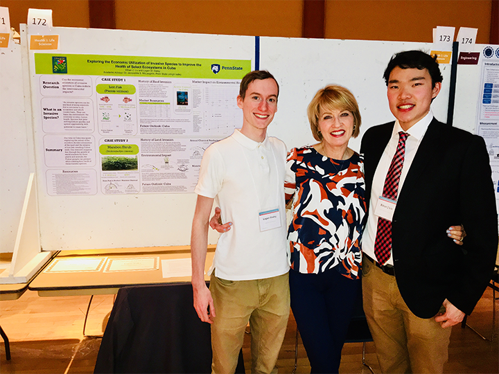 two male students and female professor in front of poster presentation