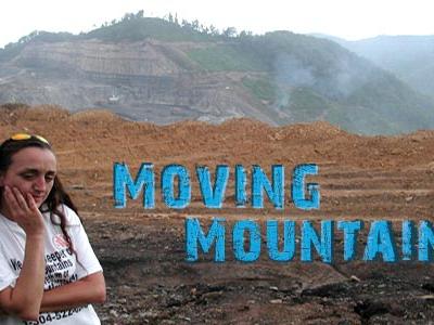 dejected female protestor holding sign in front of site of mountain-top removal mining site