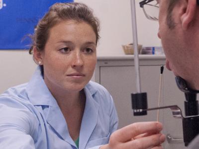 woman in lab coat swabbing a man's tongue