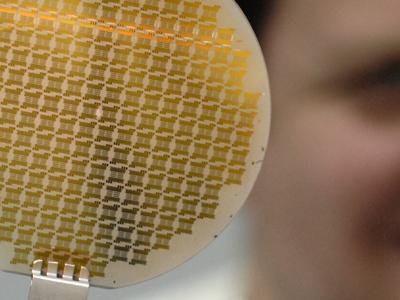 graphene wafer on metal fork, with researcher in background