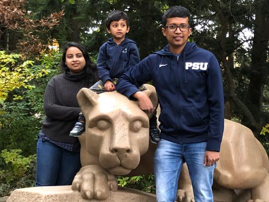 A man, woman, and boy pose for a picture beside a mountain lion statue.