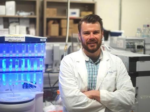 Man standing with arms crossed in a lab