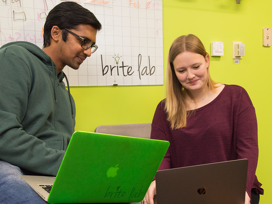 Two people hold laptop computers on their laps. 