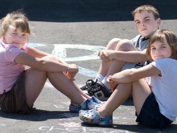 brother, two sisters, sitting on pavement