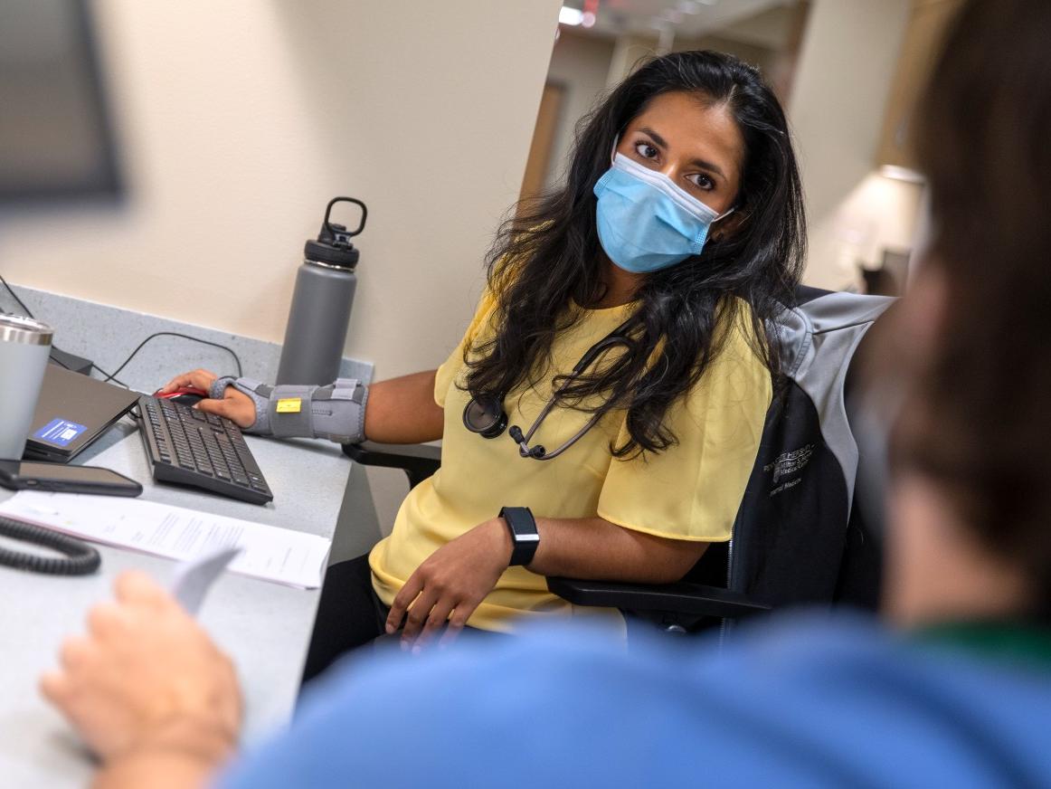 Dr. Eliana Hempel sports a fitness tracker while discussing a patient with Dr. Jeffrey Horn at Penn State Health Cocoa Outpatient Center.