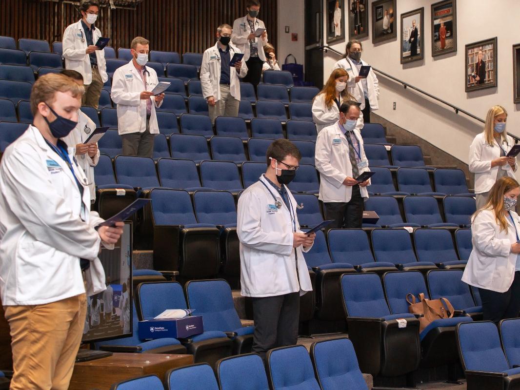 Incoming physician assistant students stand in Junker Auditorium while reciting the physician assistant professional oath.
