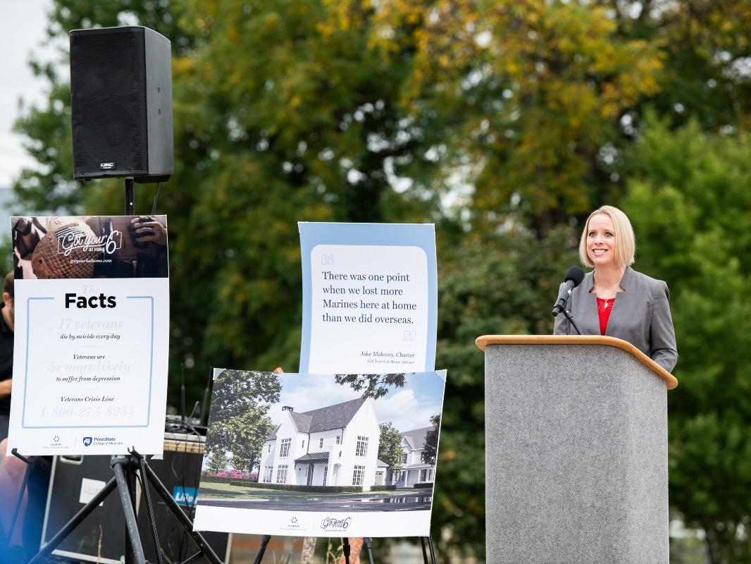 Dr. Jennifer Kraschnewski delivers a speech while standing at a podium at the groundbreaking ceremony for the first home being built as part of the Got Your 6 at Home initiative.