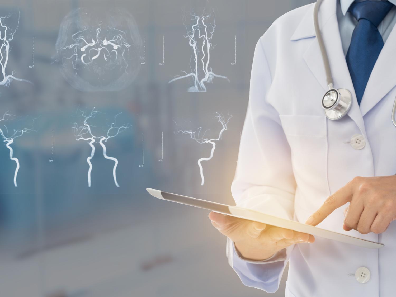 A doctor standing and pointing to a clipboard in their hands