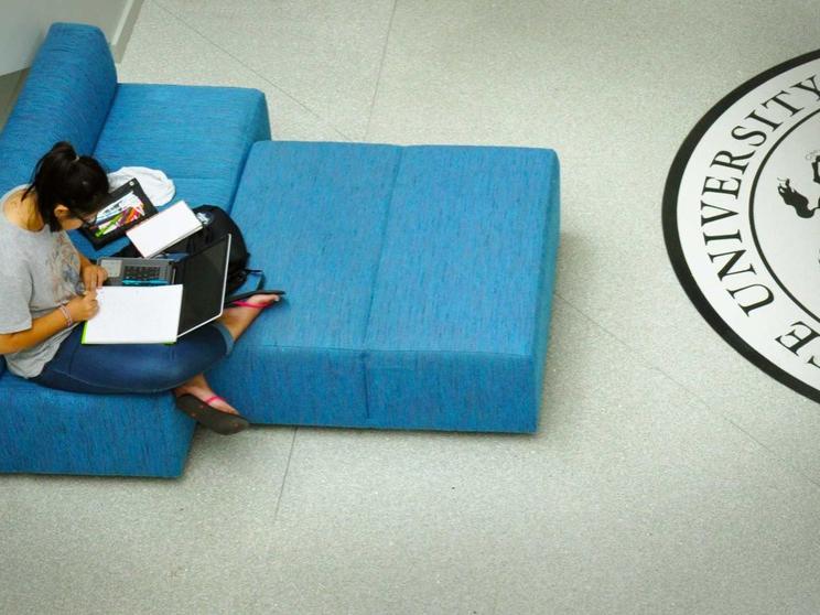 Student works on laptop and sits in chair in HUB-Robeson Center