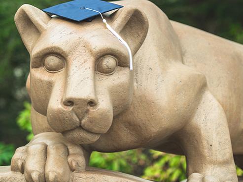 Nittany lion statue with navy graduation cap on its head