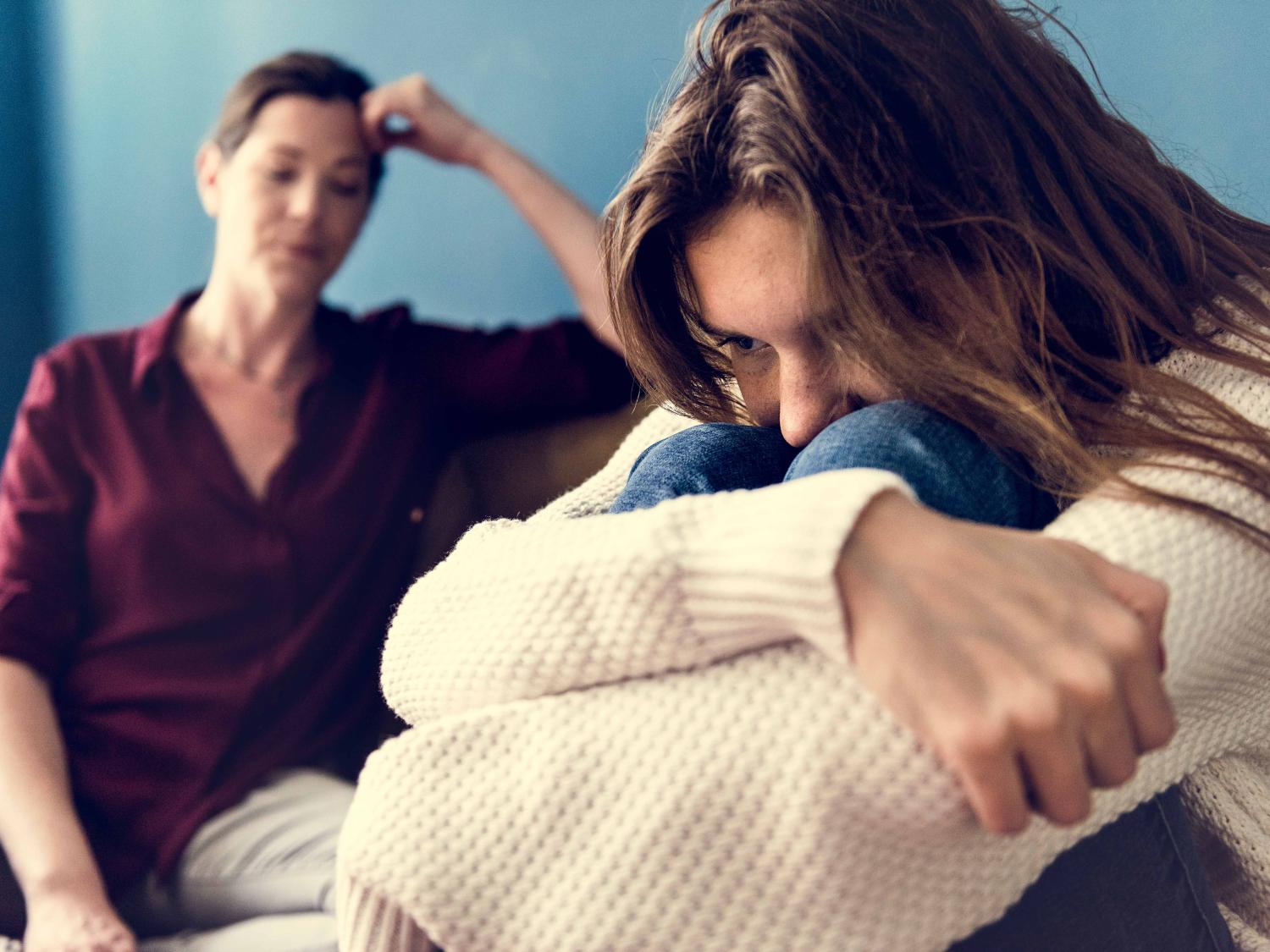 Upset teen with mother in background