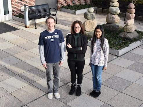Three people standing in a stone courtyard outside a building