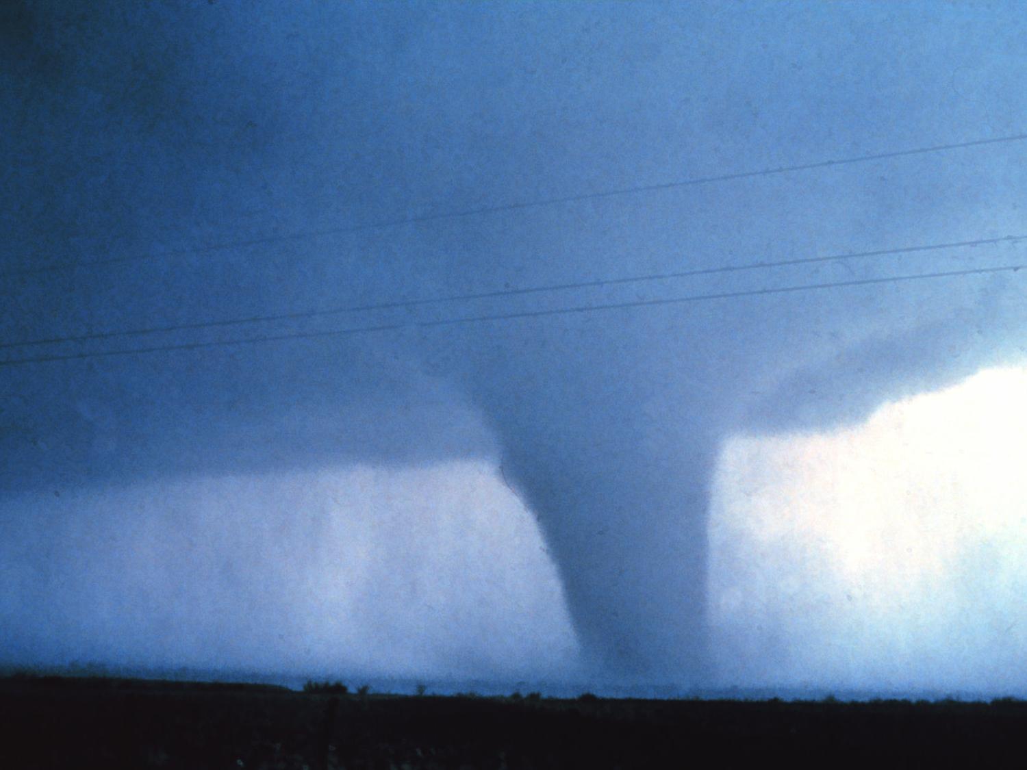 Huge dark cloud with a dark funnel coming down and touching the earth