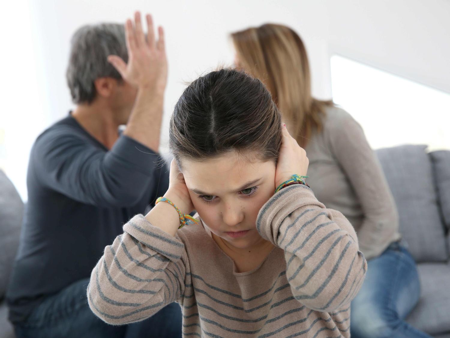 parents fighting with daughter holding her ears