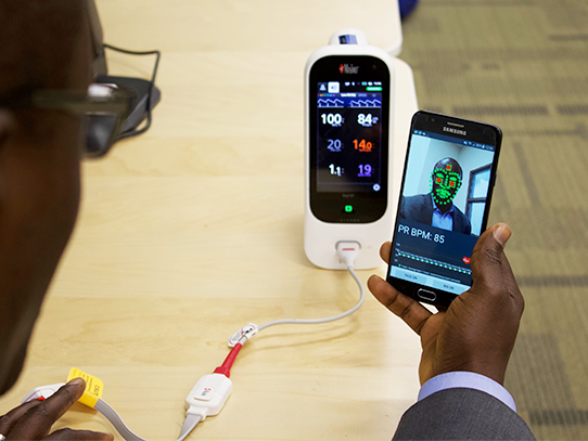 Man demonstrating how to use a mobile phone application to capture pulse rate
