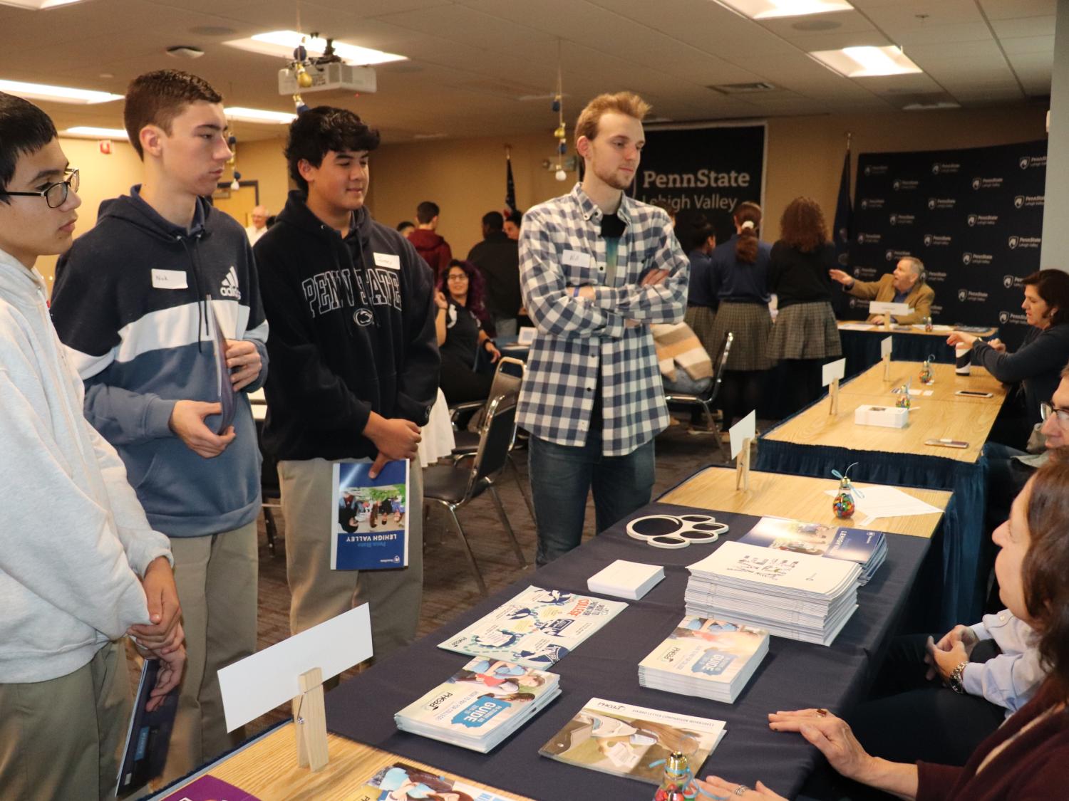 group of students at table talking with staff
