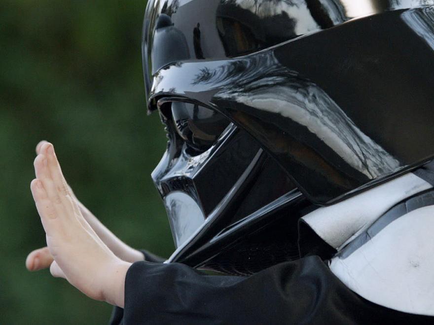A boy in a Darth Vader mask tries to use magic to move a car.