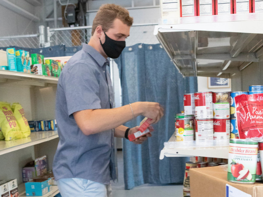 Student stocking shelves at a food pantry