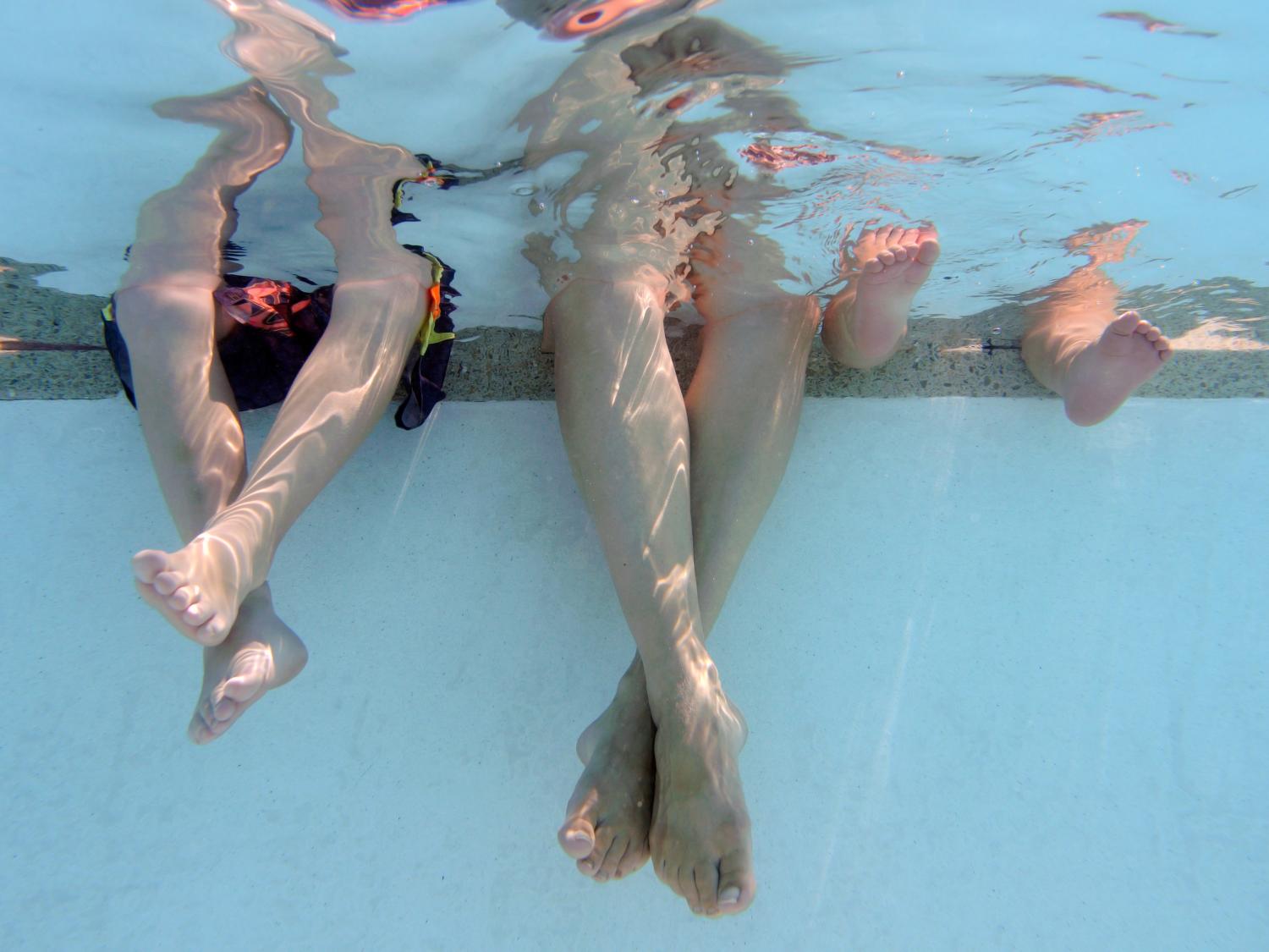 Children sitting with legs in pool