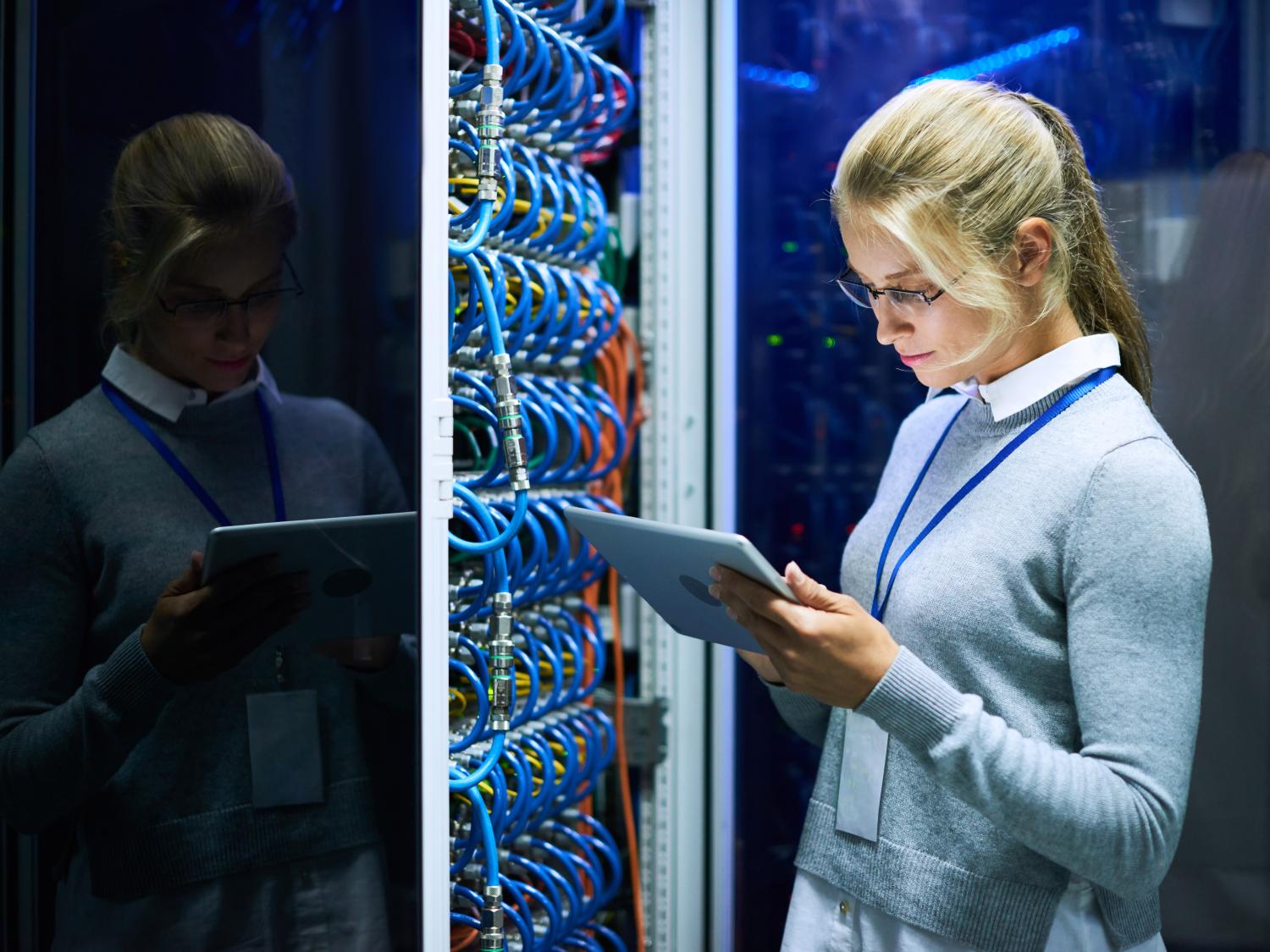 A woman uses a tablet to check the status of a server