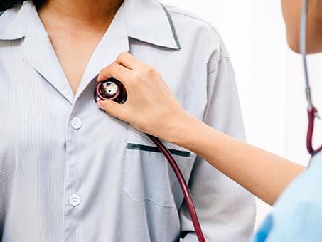 A physician checks a patient with a stethoscope.