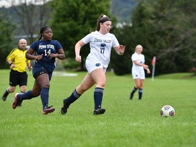 woman dribbling soccer ball down field