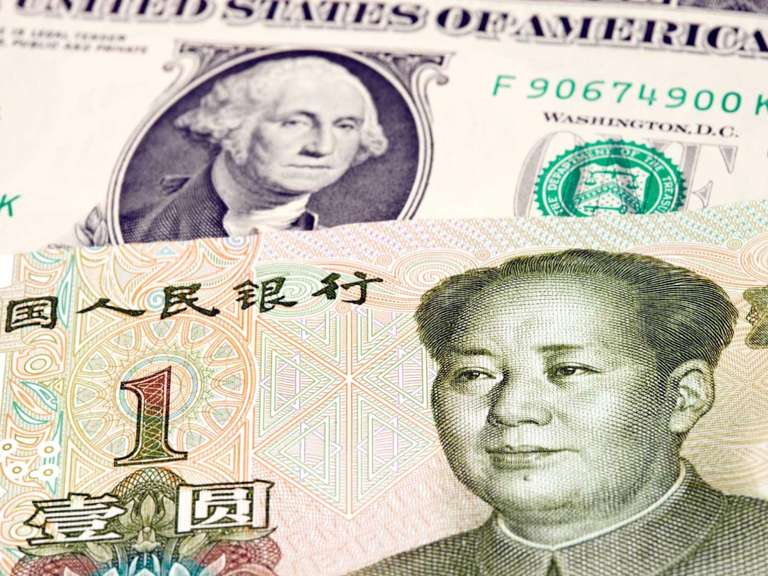 A Chinese one yuan rests on top of a US dollar.