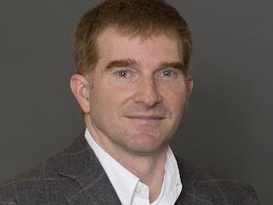 Man smiles for the camera in a gray suit