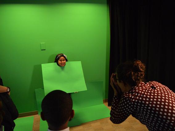 A little girl poses in front of green screen