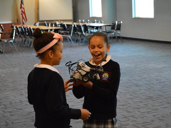 Two female students play with a LEGO robot