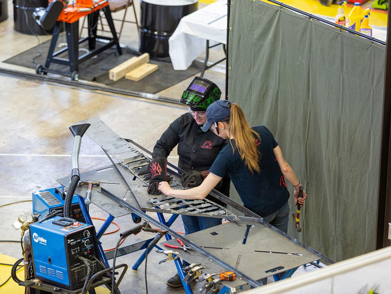 Lizz Andrzejewski, left, and Elizabeth Rothrock work on welding pieces of the chapel wall together in the Laundry Building.