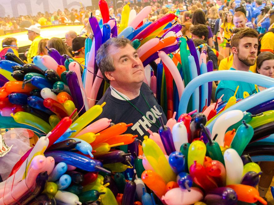 A man stands amid bunches of balloons 
