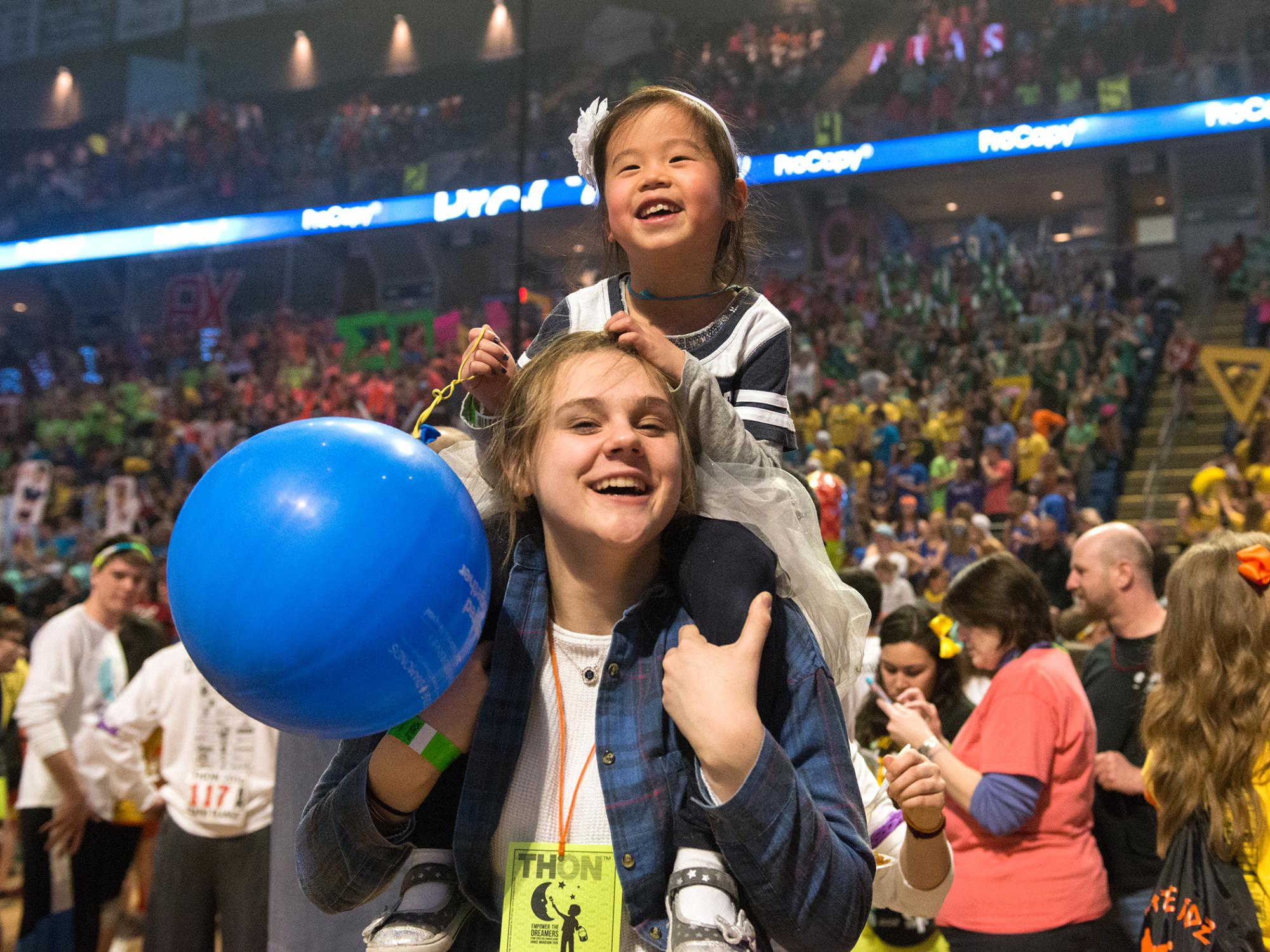 Girl riding on volunteer's shoulders at THON 2015