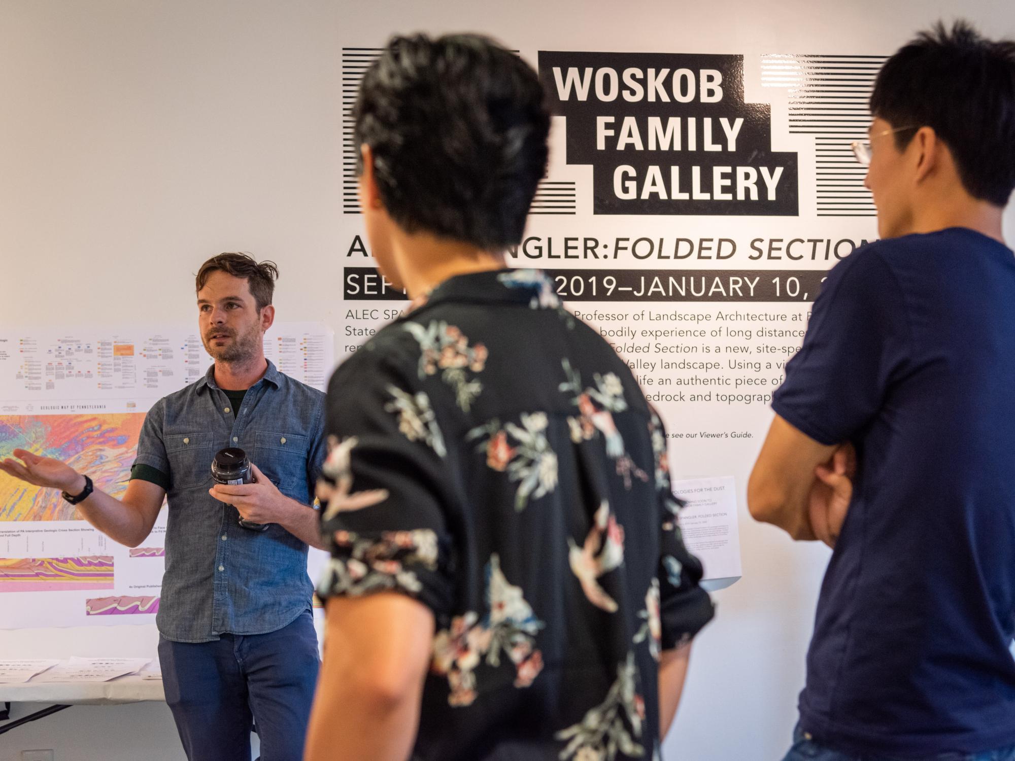 Alec Spangler explains how to implement his design to two onlooking volunteers