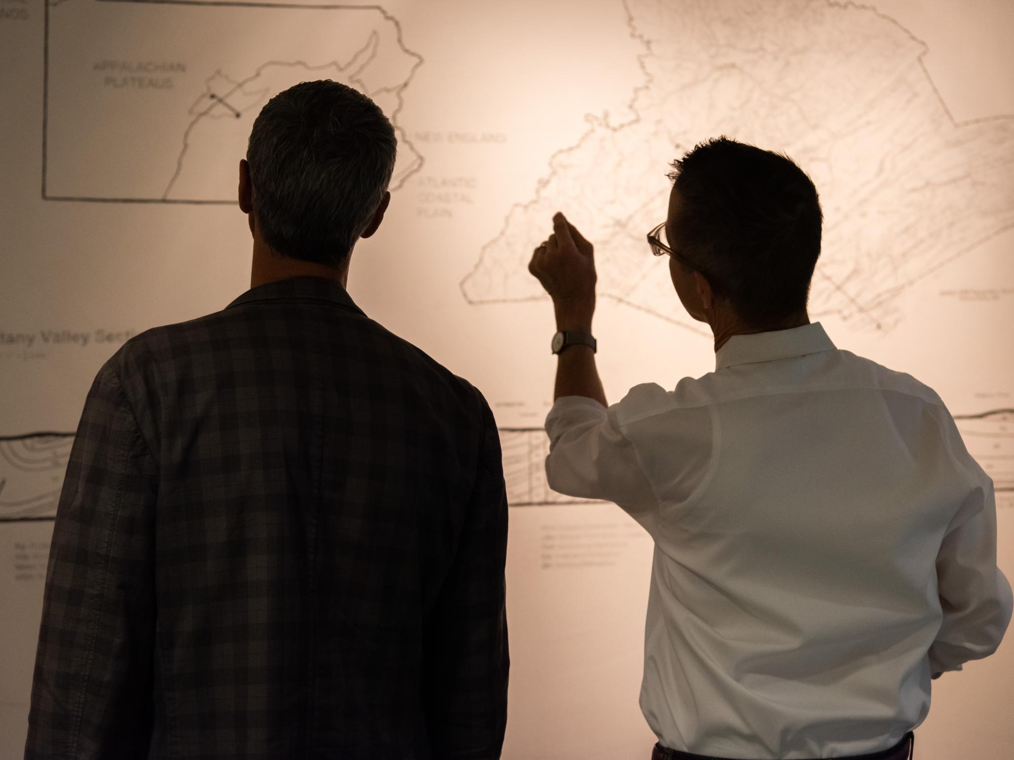 Two viewers observe the Nittany Valley section geology on the wall of the Woskob Family Gallery