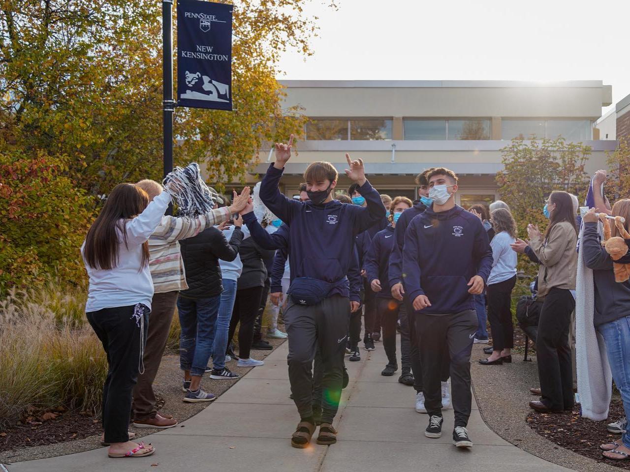 Men's soccer team walks through cheering crowd