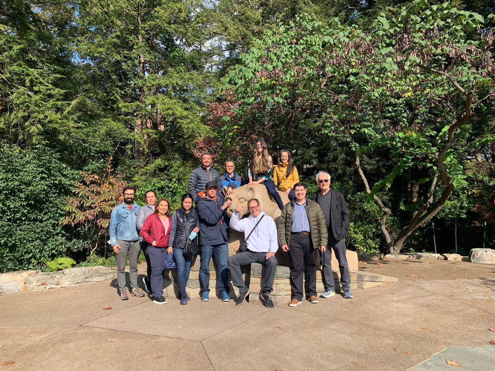 A group of people sitting around and on the Nittany Lion Shrine