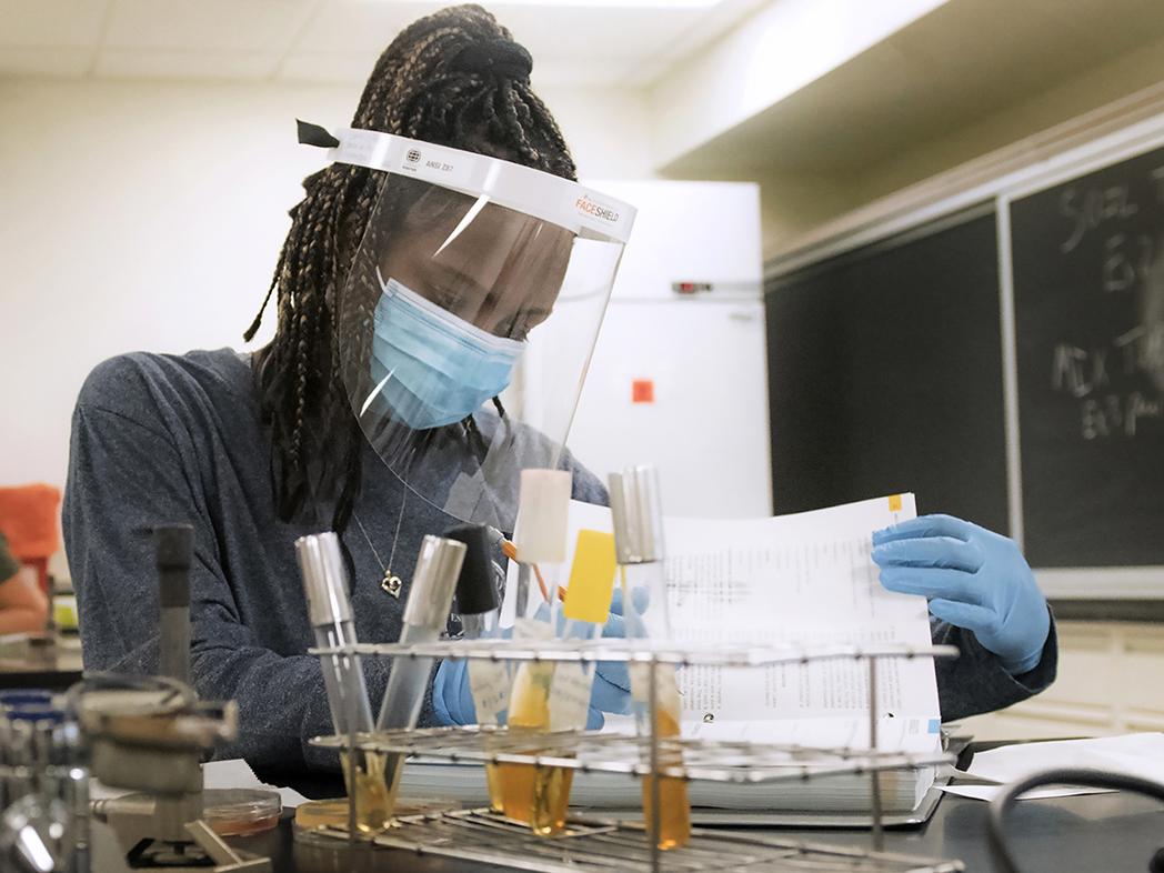 Emily Jefferson, who graduated in May 2021 with a bachelor’s degree in science and minors in Psychology and Biology, observes and records the growth of bacteria in her MICRB 202: Introductory Microbiology Laboratory class during the fall 2020 semester. Students were outfitted with new masks, face shields, and gloves prior to every lab session, and their stations were set up to provide appropriate social  distancing.
