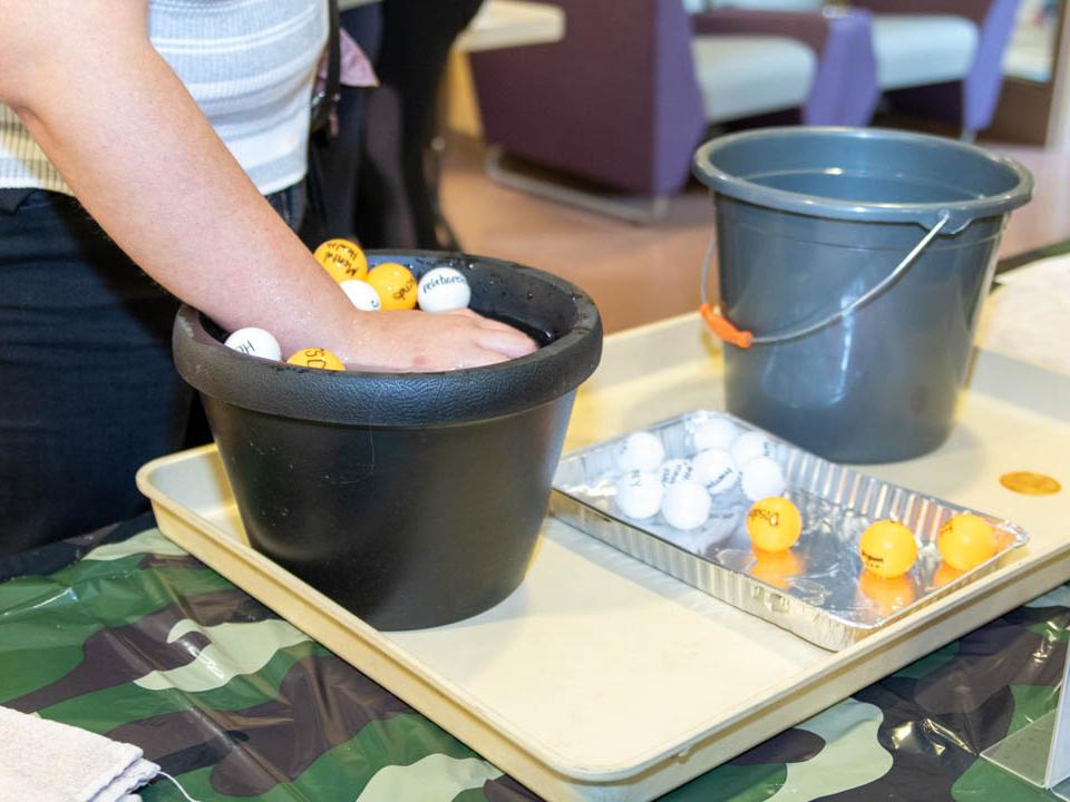 Student tries to hold down many balls in a bucket of water