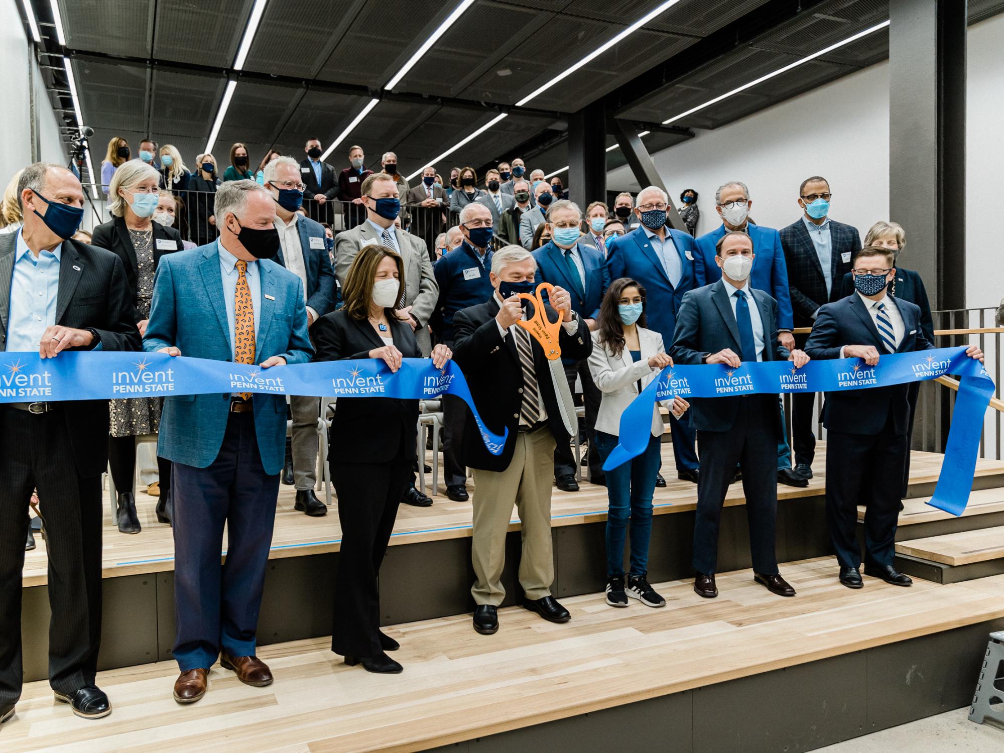 Barron cuts large ribbon held by dignitaries