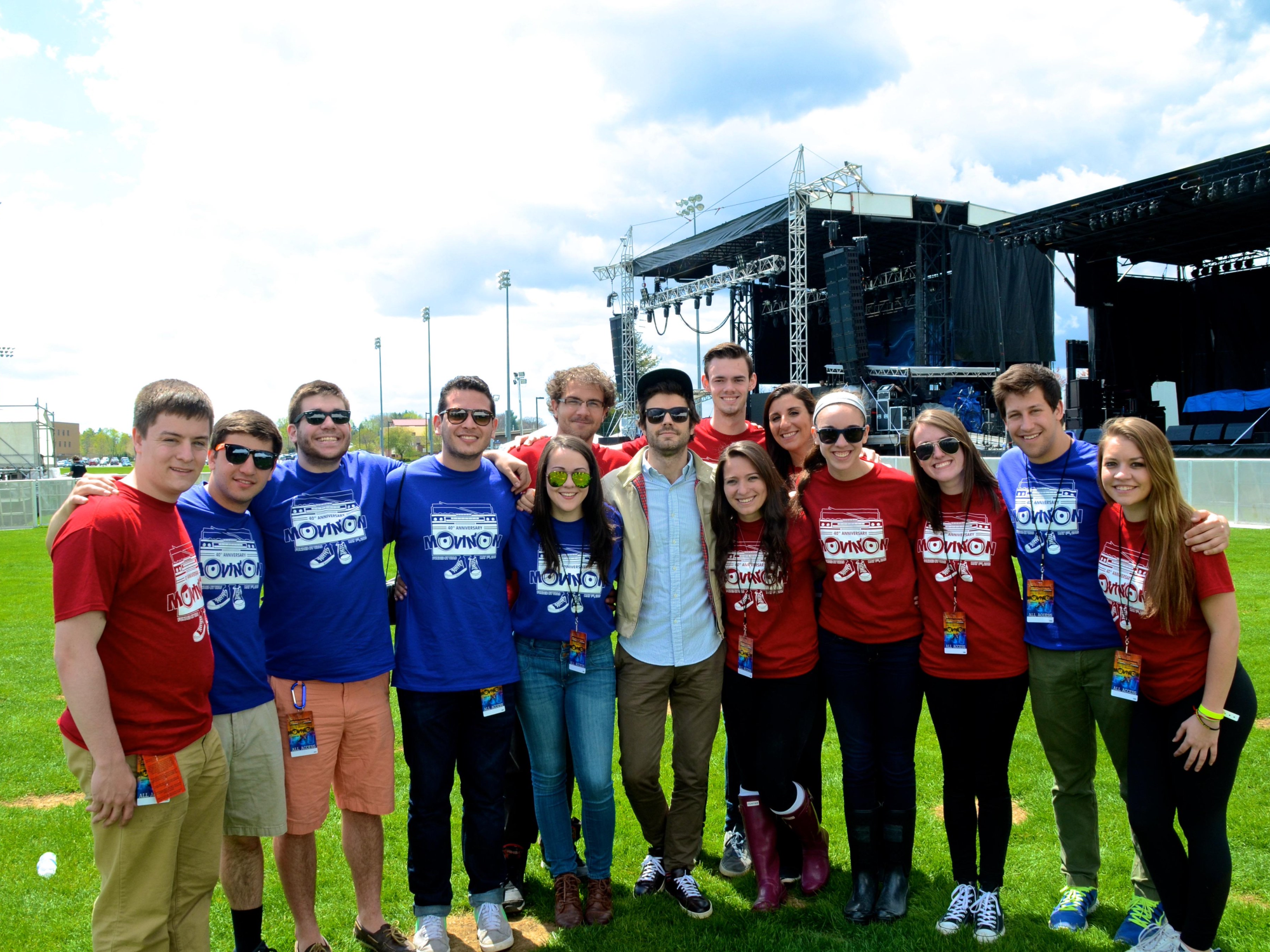 Fourteen people huddled together smiling at camera