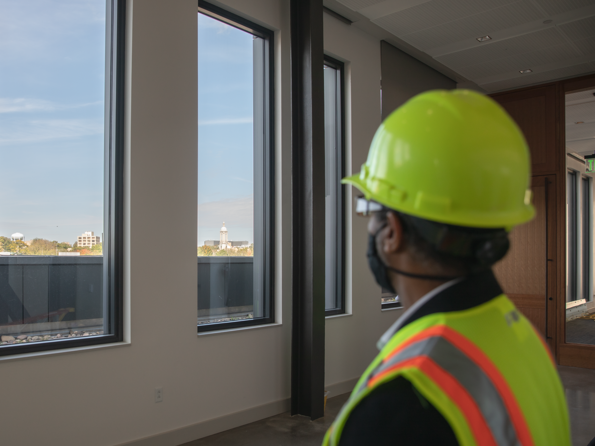 A man looks out the windows of a building to a view of Penn State's campus. 