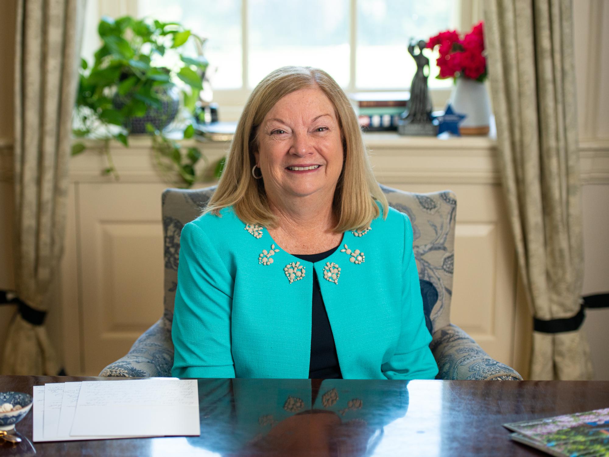 Laurie Badzek, dean of the Nese College of Nursing, sits behind her desk in her office, a stack of handwritten letters visible on her desk.