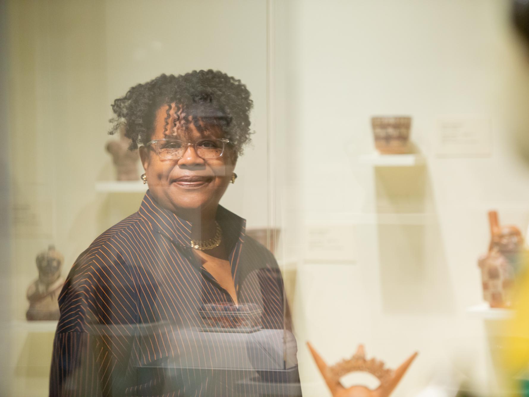 Danielle Conway, dean of Penn State Dickinson Law, gazes through a plane of glass at a collection of artwork in a display case.