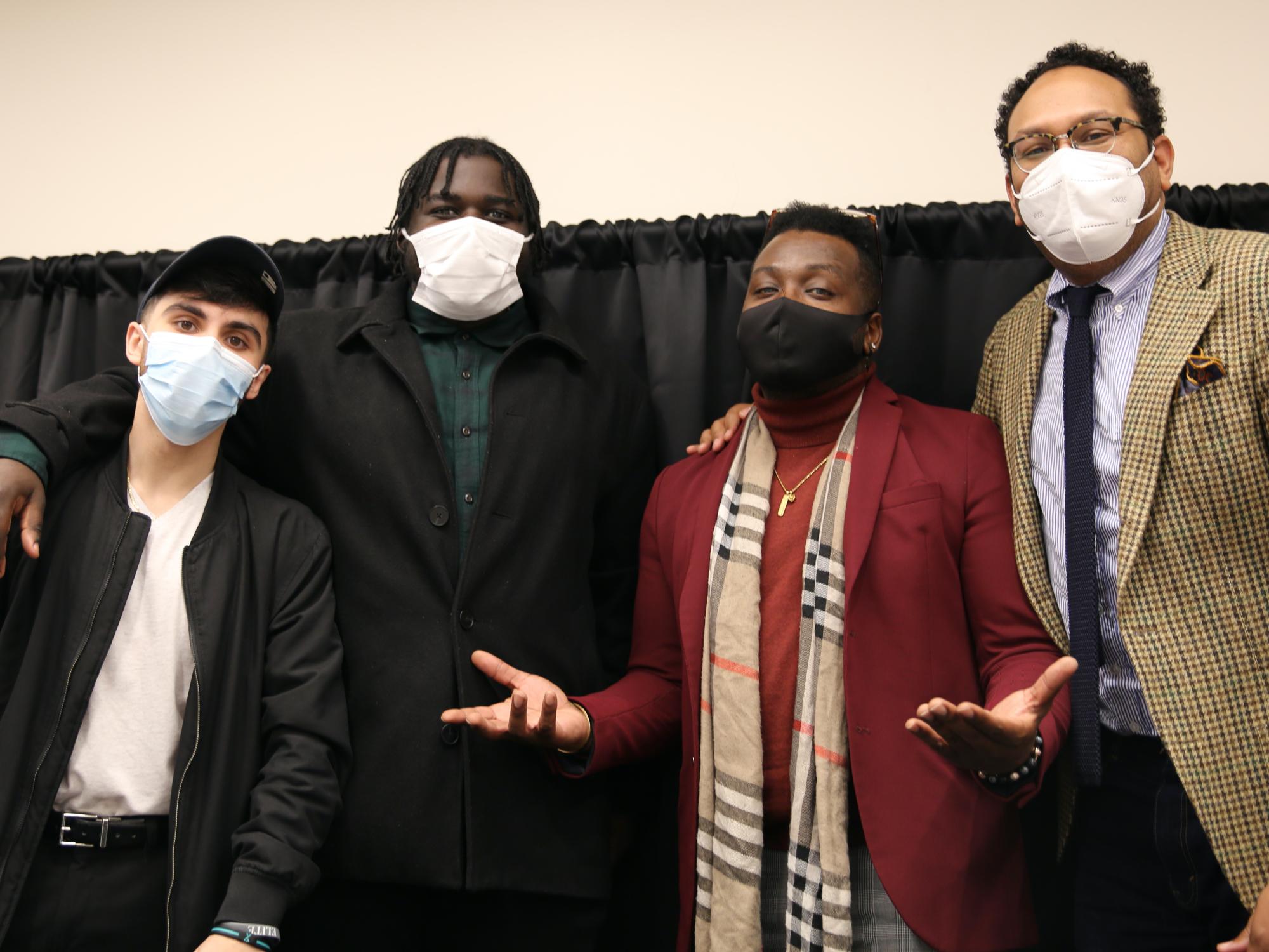 Four men stand with their masks on