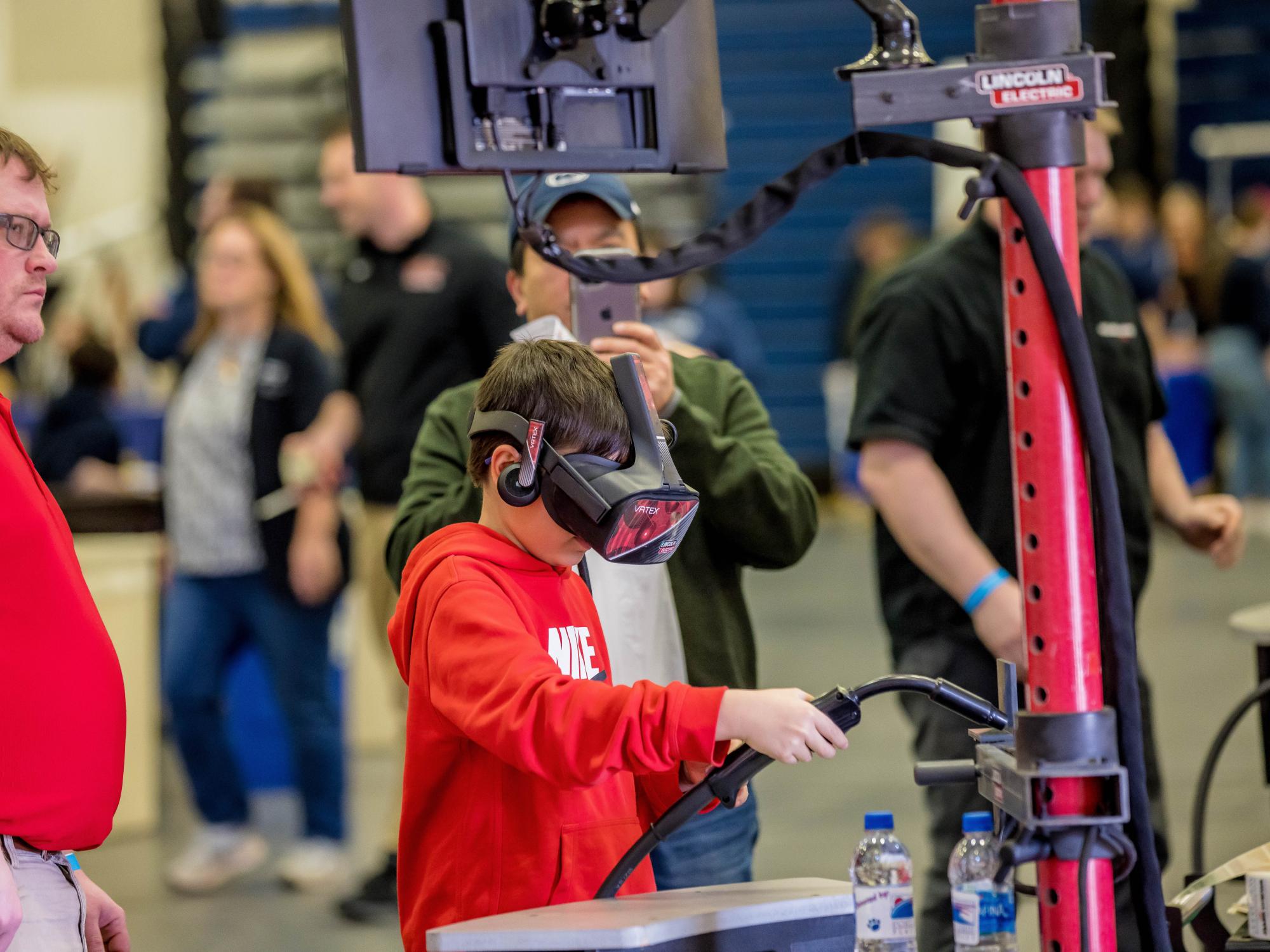 A boy tries a hands-on virtual welding simulation at the Penn State Behrend STEAM Fair.