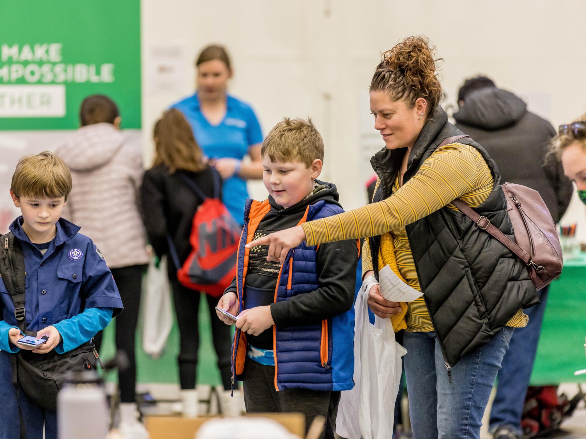 A family uses remote controls to operate a display at the Penn State Behrend STEAM Fair