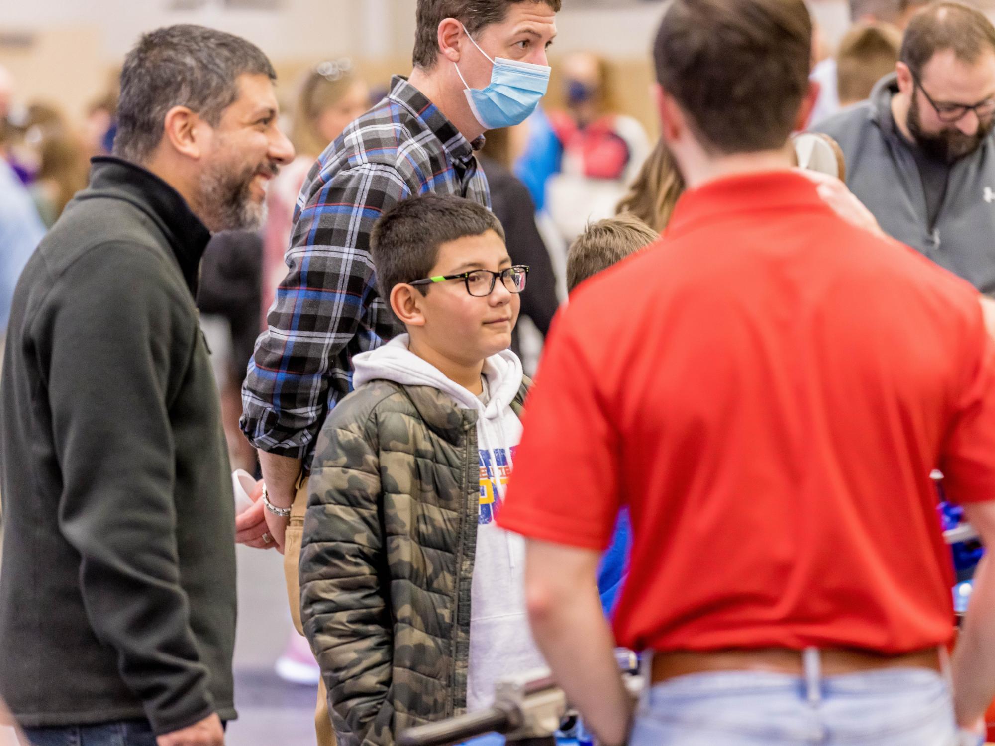 A boy and his father watch a science demonstration at the Penn State Behrend STEAM Fair.