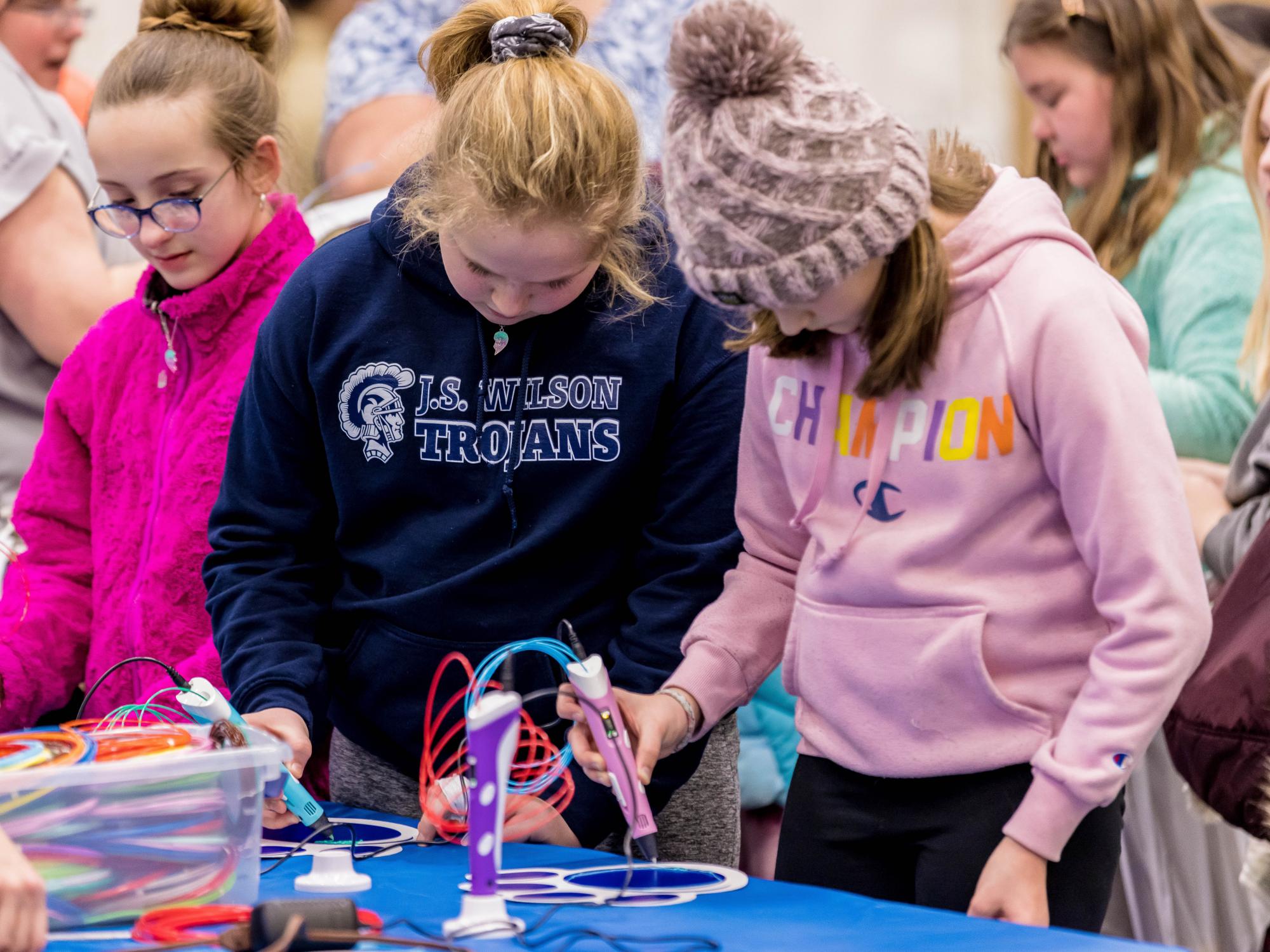 Two girls experiment with a 3D doodle pen at the Penn State Behrend STEAM Fair.